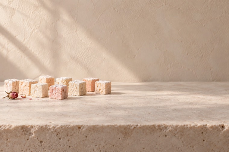 Concept: marshmallow cubes on a travertine ledge in soft light