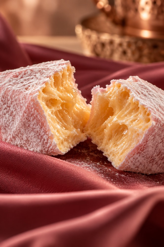 Concept image: a marshmallow torn open to show its airy honey-coloured interior, on deep rose silk